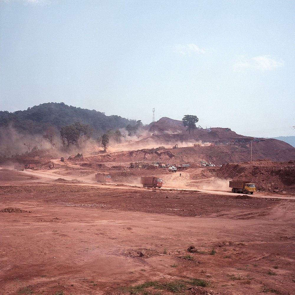 Trucks used by a Chinese company carry excavated soil from a mountain just outside of Boten for ongoing construction in the town, April 11, 2019.