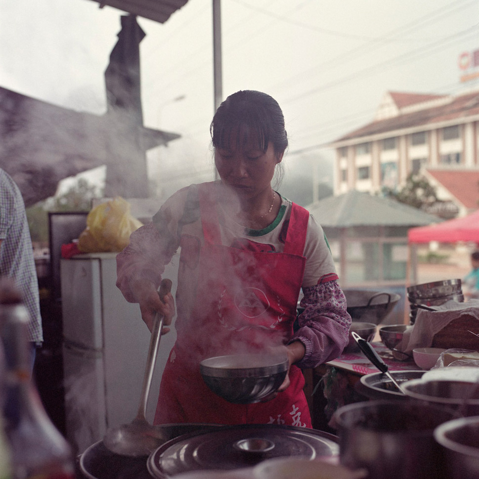 A Chinese woman prepares a bowl of noodles along the main road of Boten, January 2016.