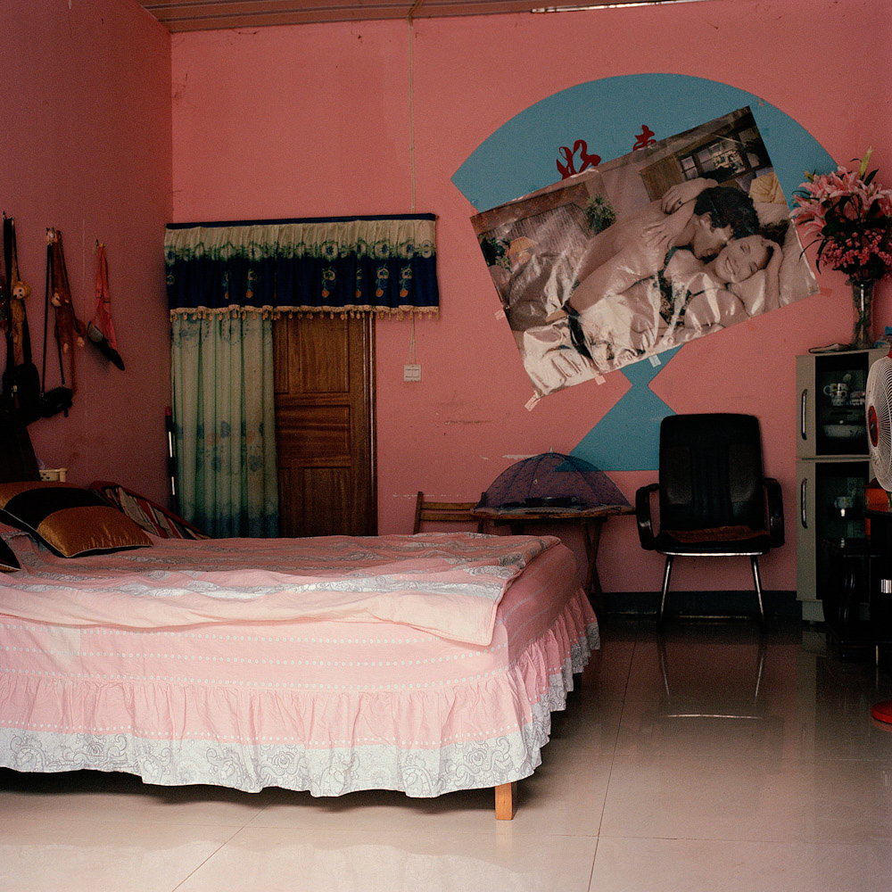A storefront set up with a bed displays a suggestive poster on the wall, on a commercial street in Boten, May 2013.
