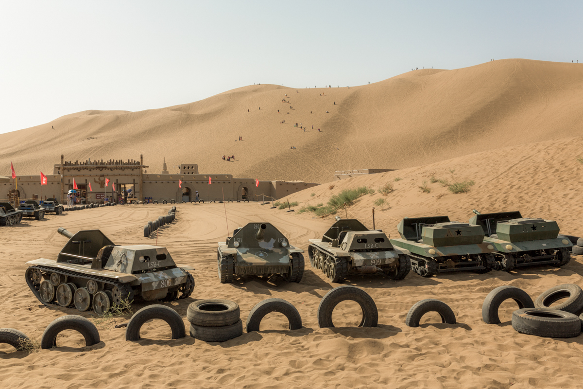 Behind a row of motorized miniature tanks, tourists climb a sand dune in the Kumtag Desert Scenic Area, a park catering mostly to Han tourists, in Shanshan county, about 56 miles from Turpan, in eastern Xinjiang, September 28, 2019.