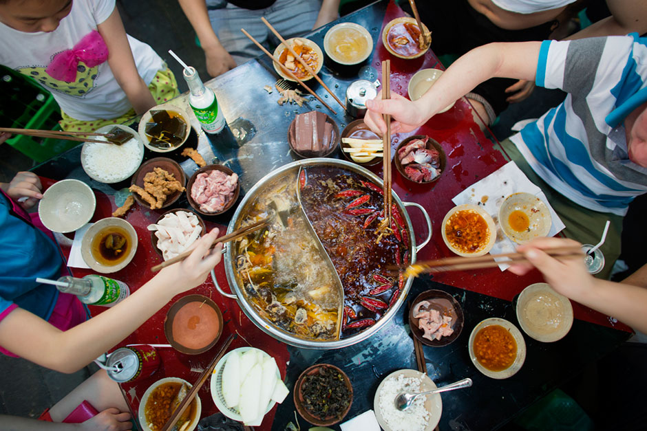 A group eats hotpot out of a split pot that separates the reddish, spicy from not spicy broth at An Pang Hotpot in an alley above Tiyu Road.