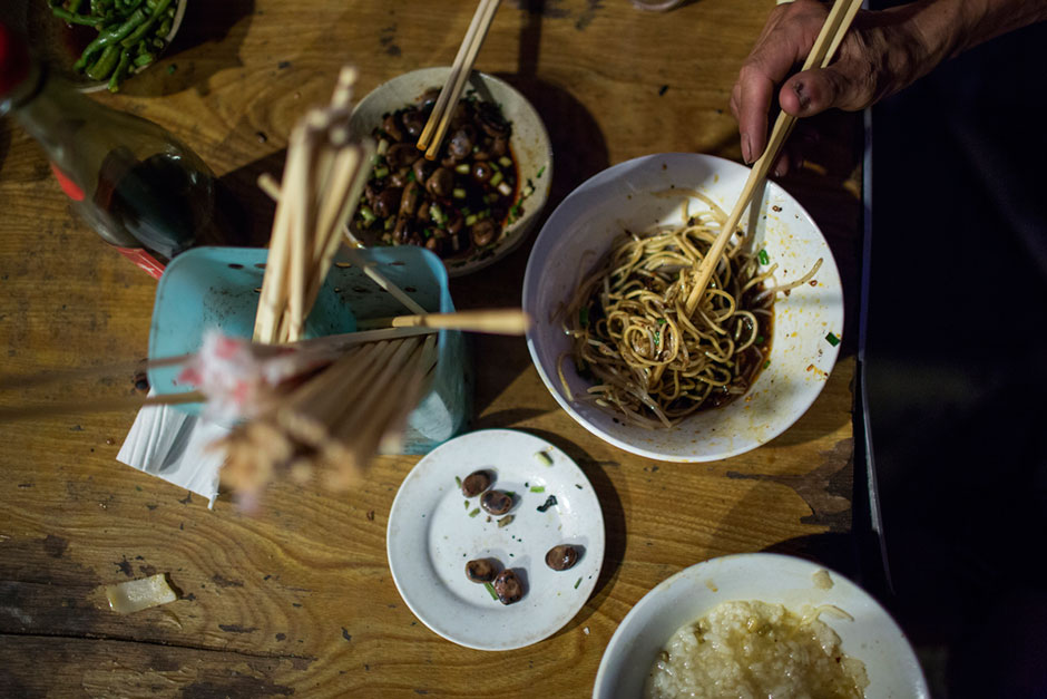Bowls of fried noodles and <em>xifan</em>, rice porridge or congee, are consumed at a small unnamed outdoor noodle cafe at the bottom of Shibati. The cook, Tong Suchun, has been in operation for about 20 years. At the time, the neighborhood was slated for redevelopment and Tong said he didn’t know what he would do after the restaurant closed. “I’ll take a break,” he says, “and then find something new.” The restaurant typically serves a couple hundred people in a night. Most spending about 15 RMB, or U.S.$2.40.
