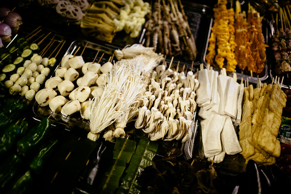 Street-side <em>shaokao</em> cooks work on Tiyu Road. The road is lined with street-side <em>shaokao</em> and hotpot restaurants.