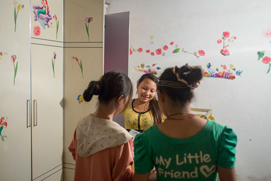 Jie talks with two neighborhood girls in her room decorated with stickers from the Disney movie “The Little Mermaid” and other designs.