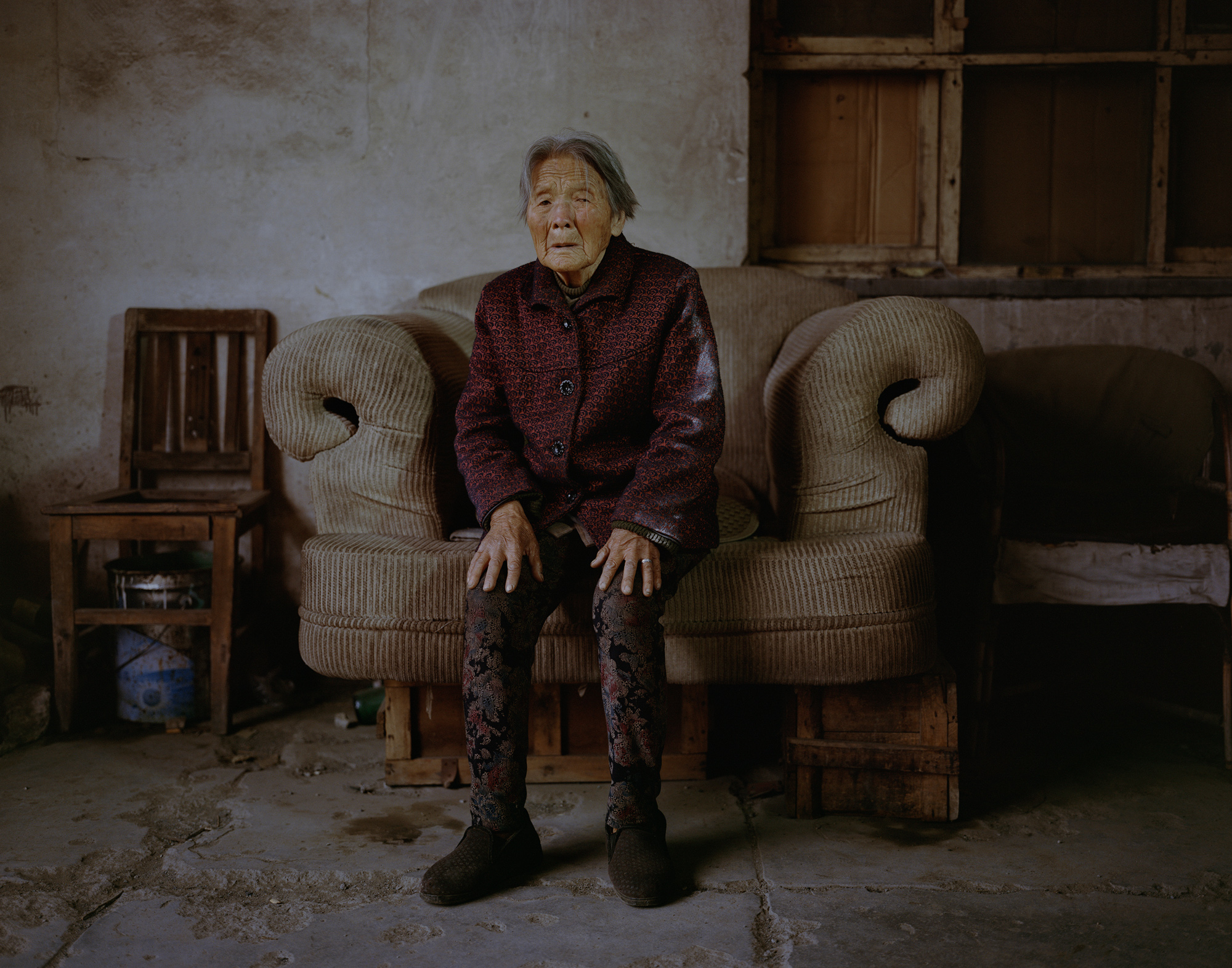 Ma Yulan, 82, sits in the hallway of her apartment building in Xiahuayuan. Ma moved here with her son 30 years ago when he found a job at a coal mine. During the local coal industry’s peak, 89 mines were operational. Now there are fewer than 10. 