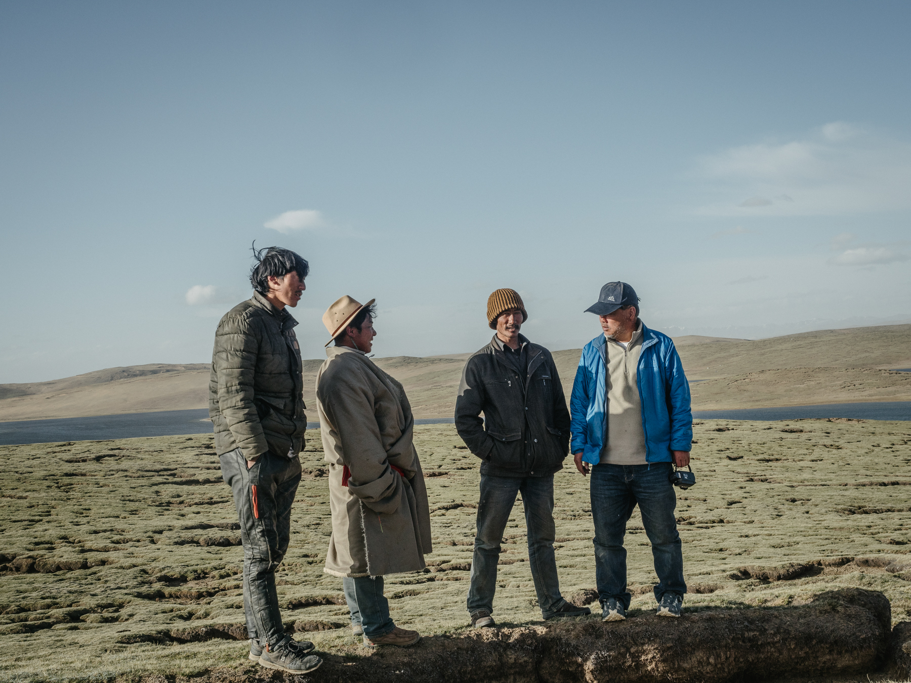 Local Tibetans (left three) greet Yang at the campsite next to the lakes Gangnagemacuo and Rigecuochama. The ground that they stand on shows visible cracks, with sections of the frozen ground having melted and collapsed. This exposes the thin layer of fertile soil to strong winds and burrowing animals, like hares and pikas, causing further degradation and eventual desertification. Yang says that climate change is accelerating desertification of the mountain grasslands.
