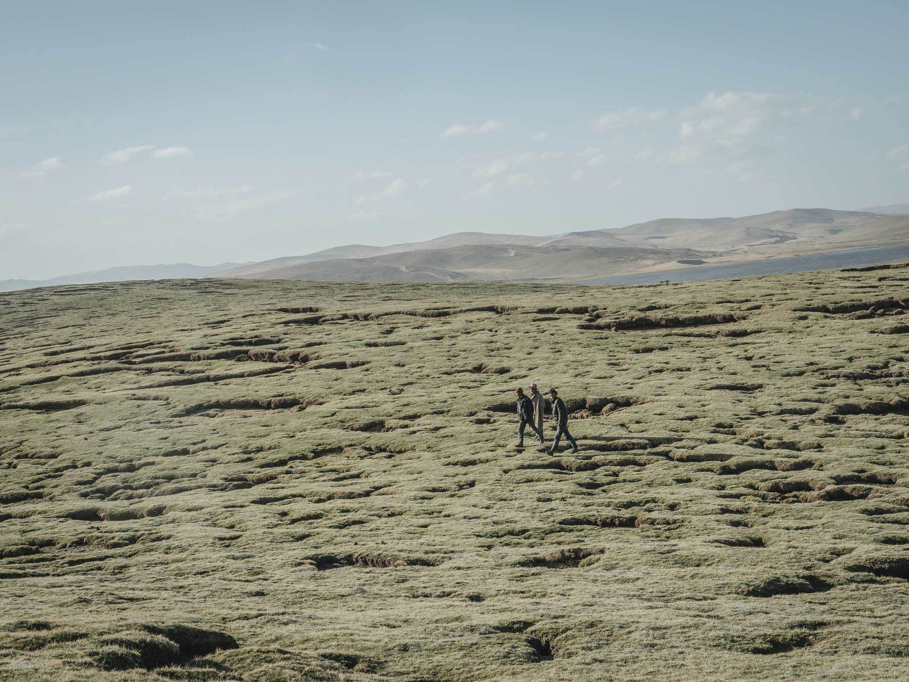 Local Tibetans walk across the grasslands between Gangnagemacuo and Rigecuochama. “The grassland here may look green and healthy, but the pockmarked cracks in the grass are the first signs of desertification starting,” says Yang.