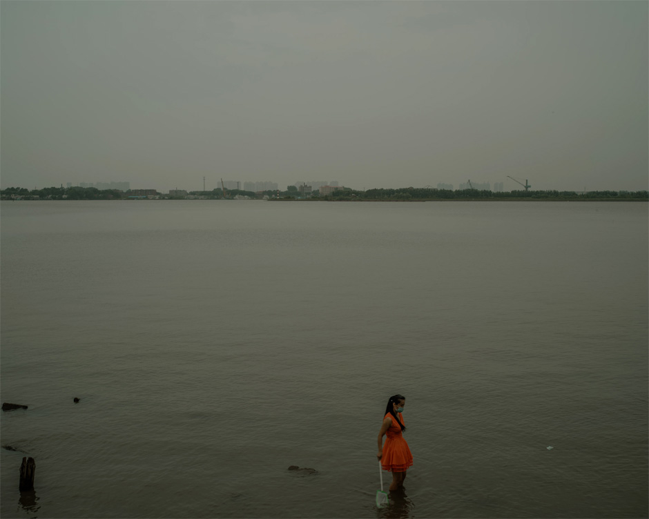 A woman wears a facemask and holds a fishing net while standing knee-deep in the Songhua River in Harbin. A tributary of the Amur, the Songhua is another point of connection between the two countries. An explosion at a Chinese chemical plant in November 2005 spilled 100 tonnes of nitrobenzene into the Songhua—a spill local officials were unable to conceal when it became clear the pollutants would quickly drain across the border into Russia.