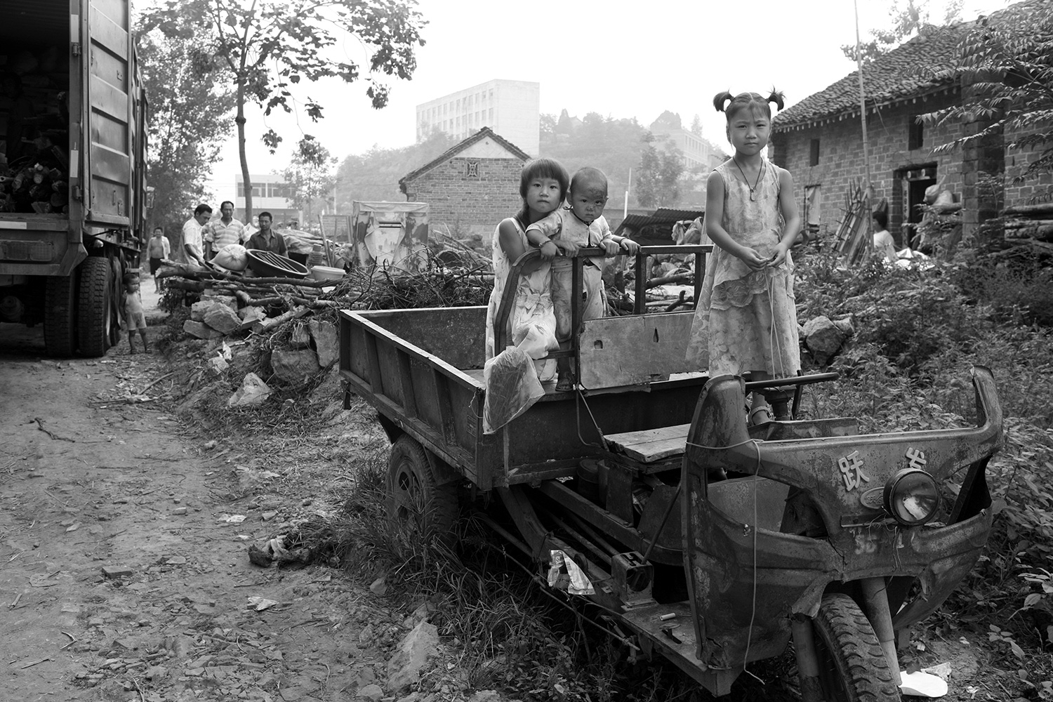 Three children stand in their family’s utility vehicle at a demolition site in Jinhe, Xichuan county, Henan province, August 2011, as villagers prepared to move out as part of a relocation program.
