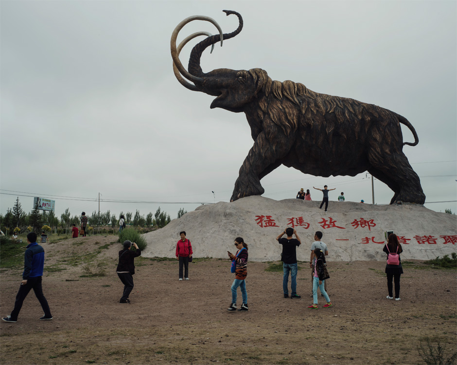 Tourists visit a wooly mammoth statue, built to commemorate a fossil discovery, in Mammoth Park in the Jalainur district of Manzhouli.